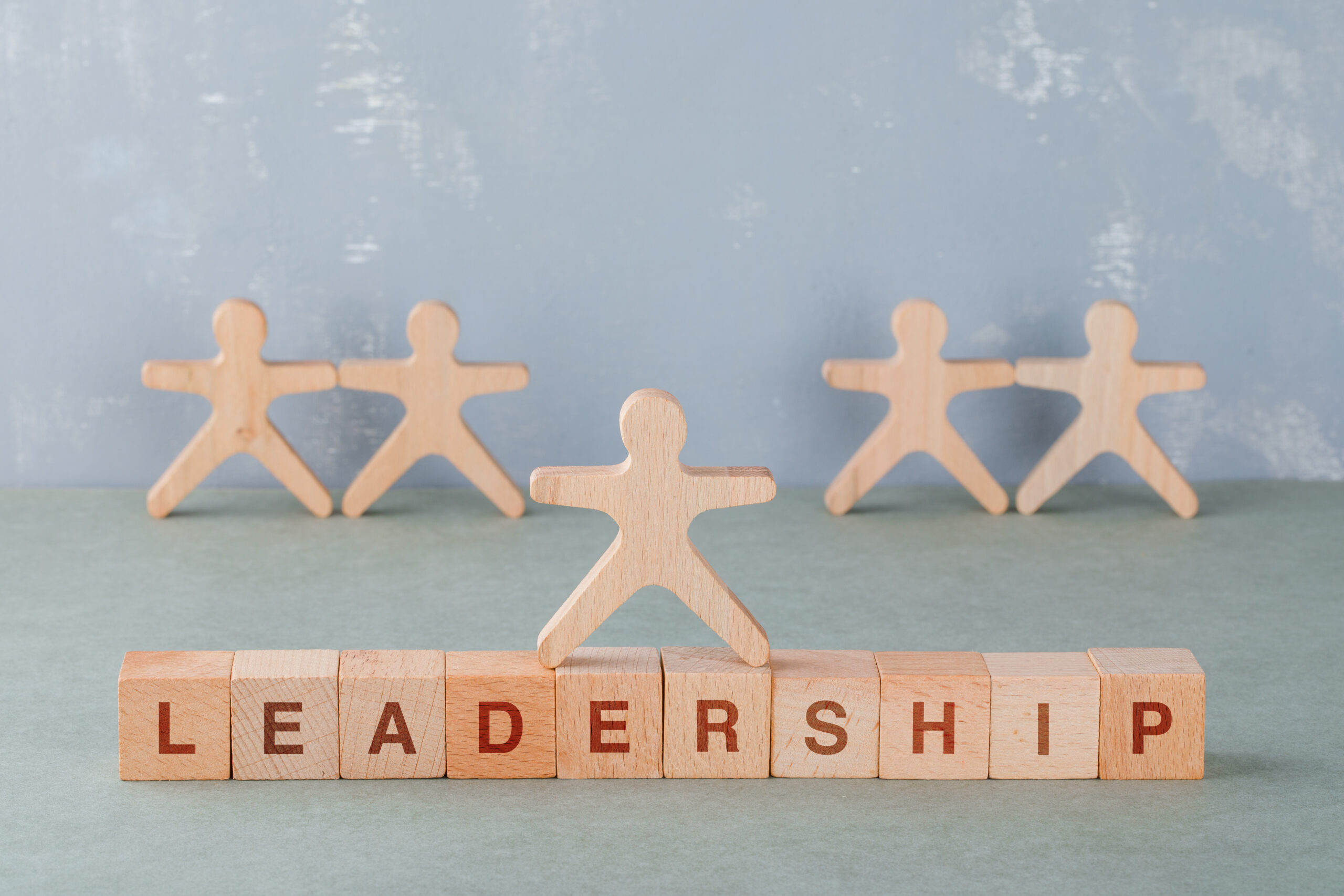 Team building and business concept with wooden blocks with words on it, wooden human figures on sage color background side view. horizontal image